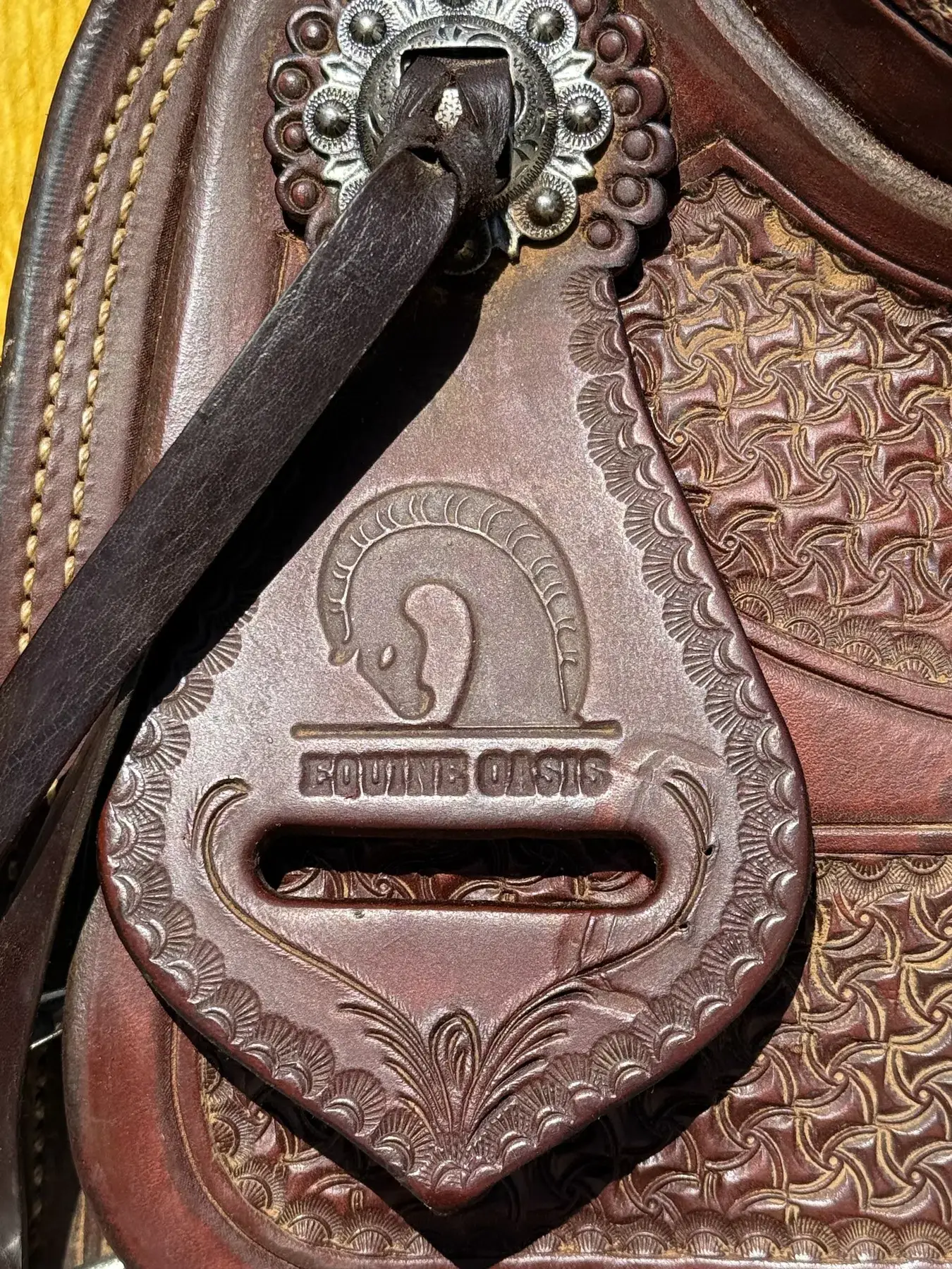 Equine Oasis brand stamp and silver concho close-up